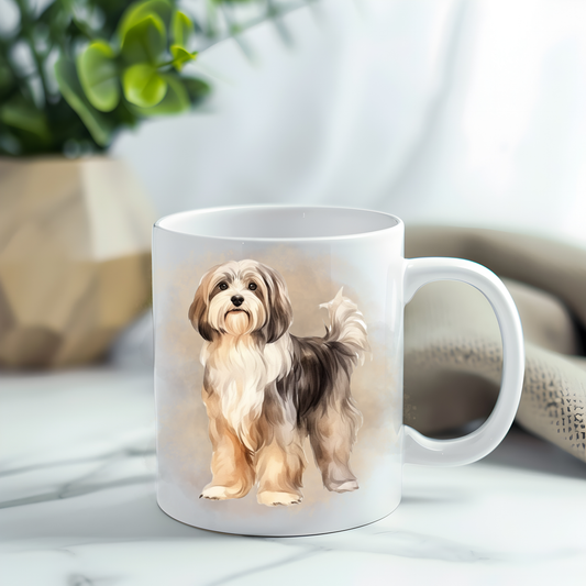 A Havanese dog in a standing position on a white ceramic mug which has been placed on a grey marble surface.  A green plant decorates the left corner.