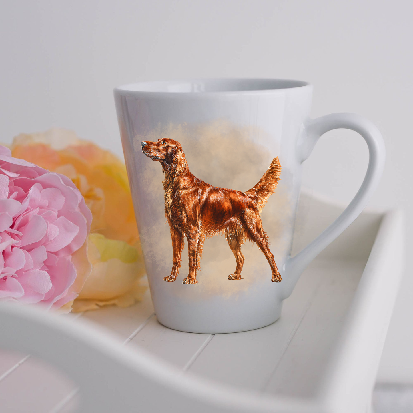 A lovely Irish Setter Collie is standing in profile on a white ceramic latte mug in a smoky background and facing his left side.  The mug is placed on a white tray with pink and yellow flowers. 