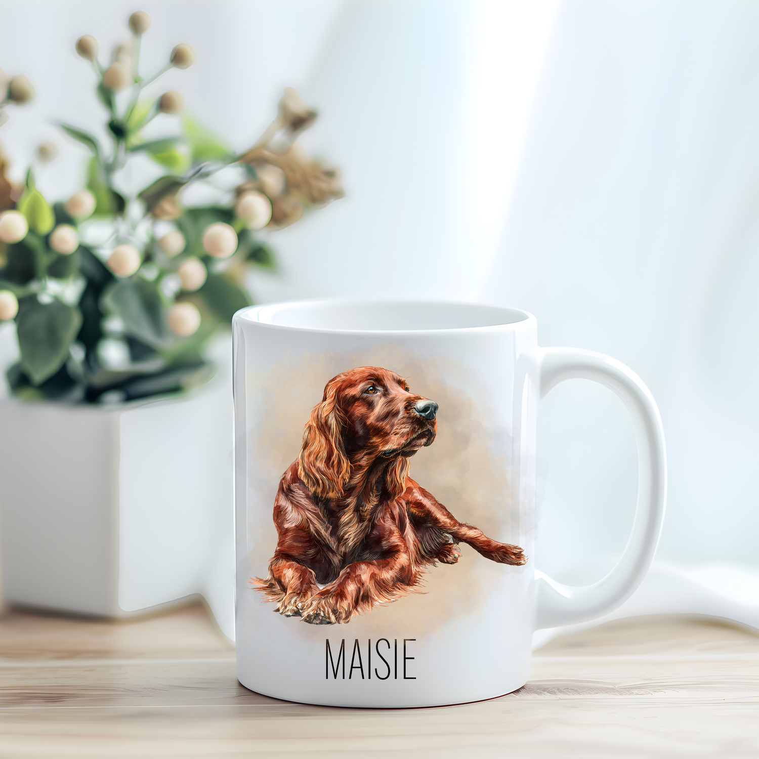This coffee mug features an Irish Setter on a white ceramic mug which has been placed on a light wooden surface.  A green and white plant sits on the left side of the image in a square plant pot.