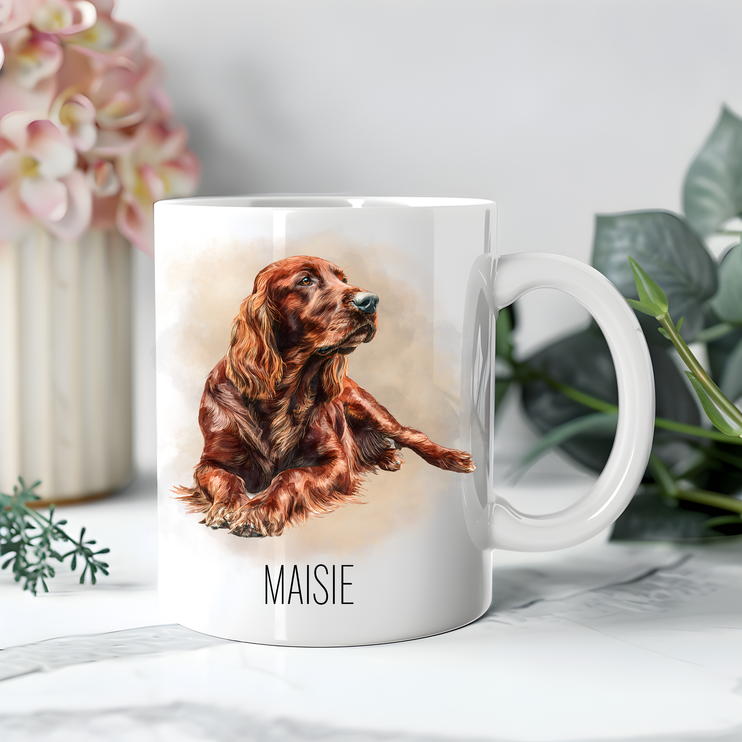 Personalised coffee mug featuring an Irish Setter on a white ceramic mug which has been placed on white surface.  A large pink flower sits to the left with dark green foliage on the right to accessorizes the image