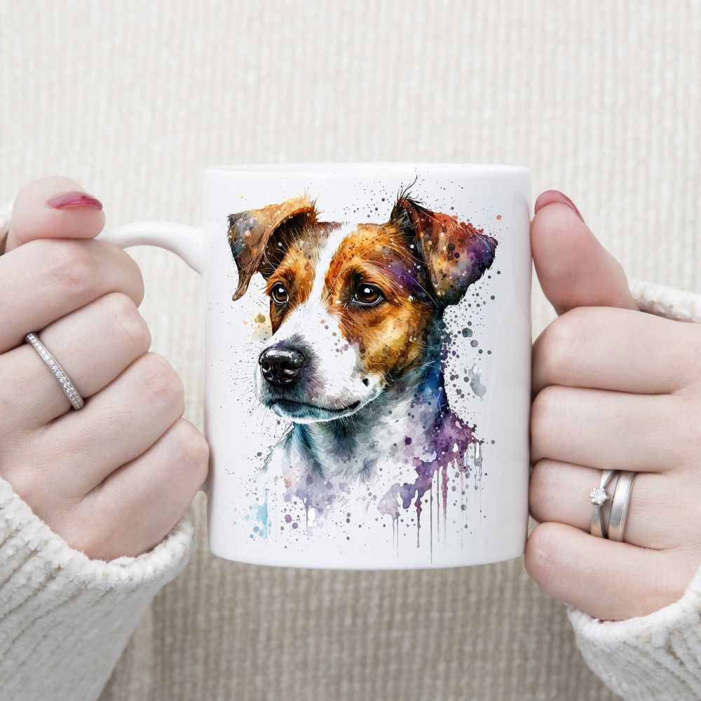 A water-colour image of a Jack Russell Terrier on a white ceramic mug.  A splash effect decorates the background.  A woman wearing rings is holding the mug in two hands.