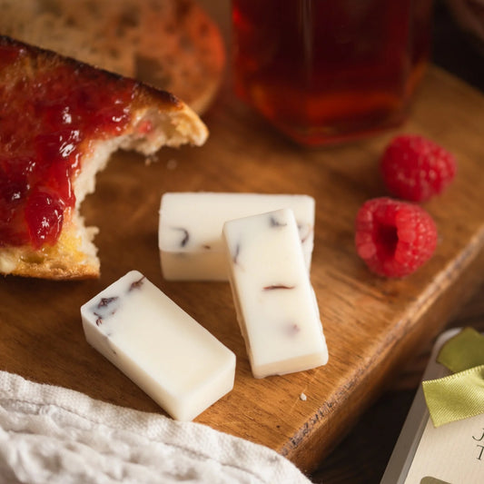 3 cubes of wax melts on a board with some jam on toast.