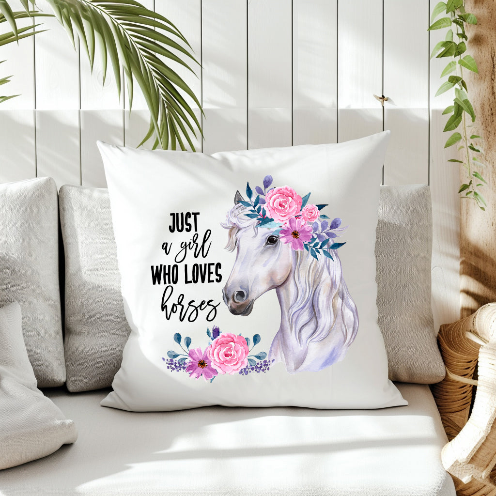White cushion with a white horse head decorated with pink flowers and a quote of Just a A Girl Who Loves Horses.