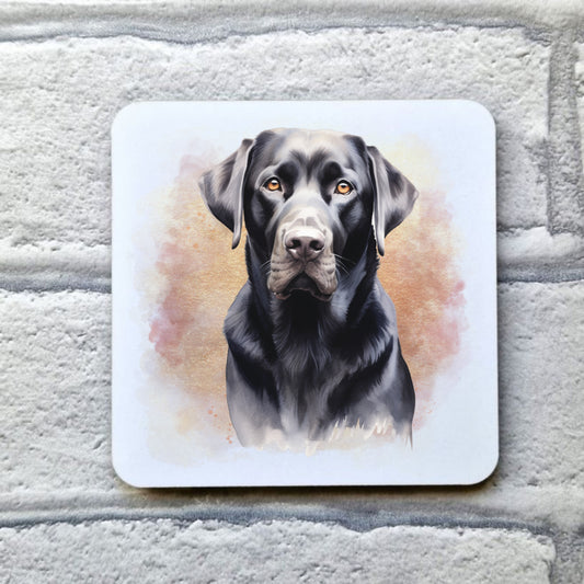 A White drinks coaster with a head shot of a Black Labrador with a pink and gold misty background.  The coaster is placed on a grey, brick effect surface.
