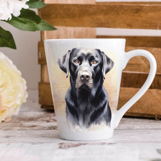 A 12oz white ceramic latte mug with a printed image of a black Labrador dog facing forward, positioned on a wooden surface with a blurred background.