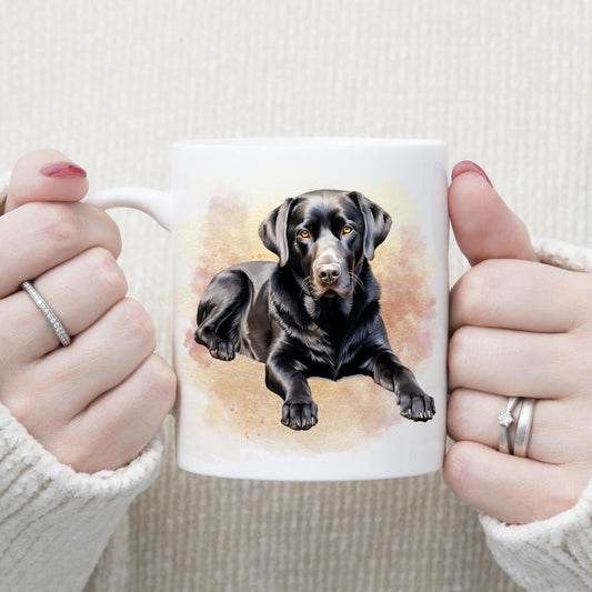 A black Labrador dog is laid among a pink and gold misty background on a  white ceramic mug. A woman is holding the mug