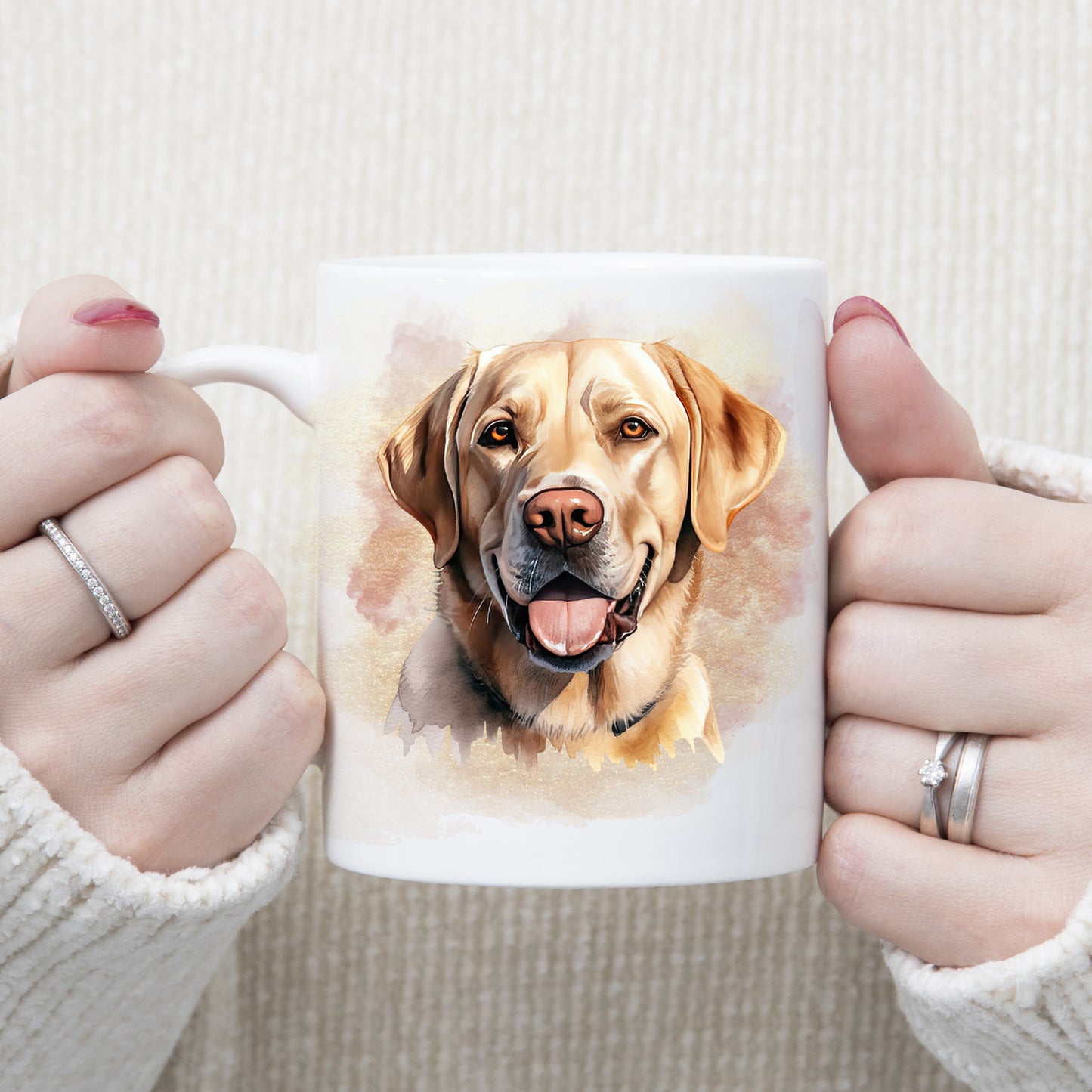 A Yellow Labrador dog with a amber eyes and a tongue out adorns this white ceramic mug.  A pink and gold misty background decorates the mug which is being held by a woman with both hands.