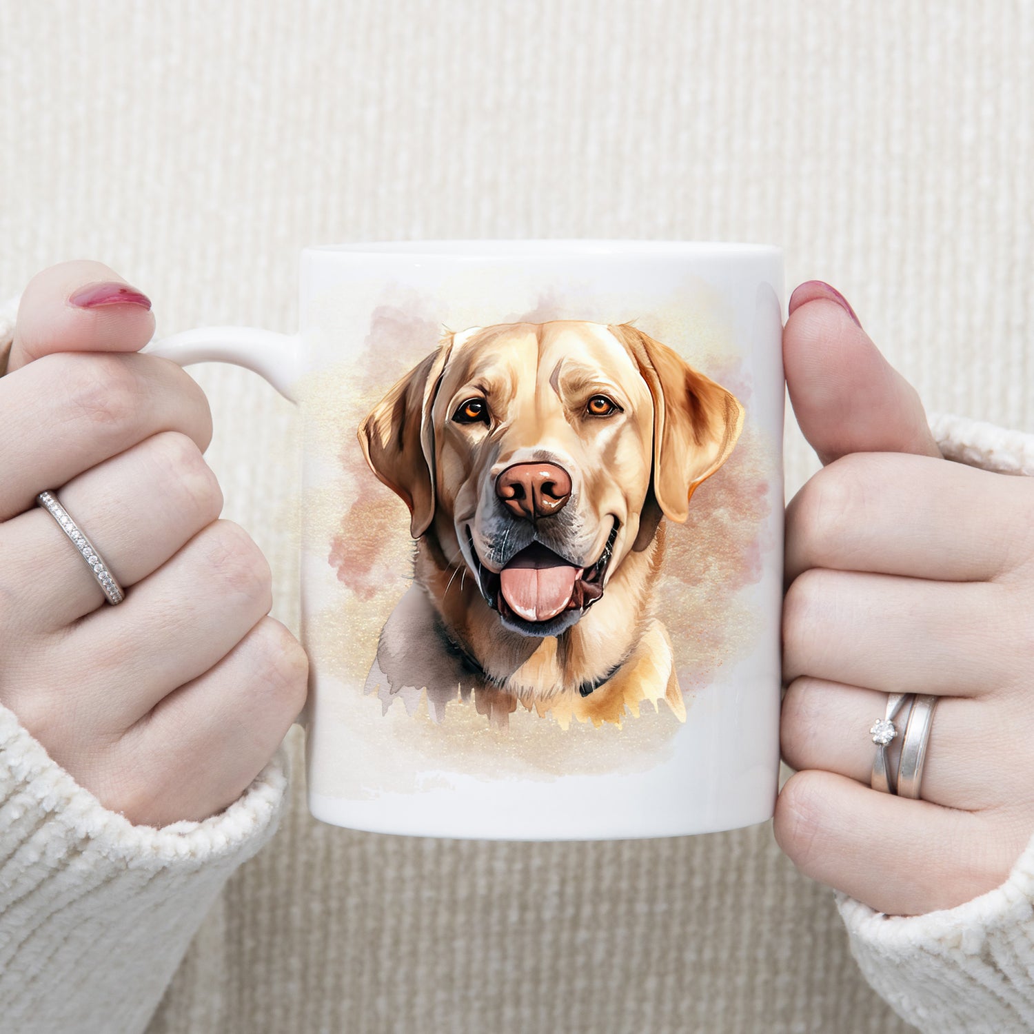 A Yellow Labrador dog with a amber eyes and a tongue out adorns this white ceramic mug.  A pink and gold misty background decorates the mug which is being held by a woman with both hands.