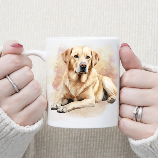 A yellow Labrador dog is laid in front of a pink and gold background on a white ceramic mug.  A woman is holding the mug.