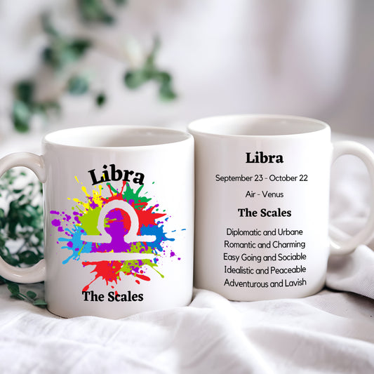 Two white ceramic coffee mugs with colorful zodiac sign Libra symbol and characteristics printed on them, placed on a light background.