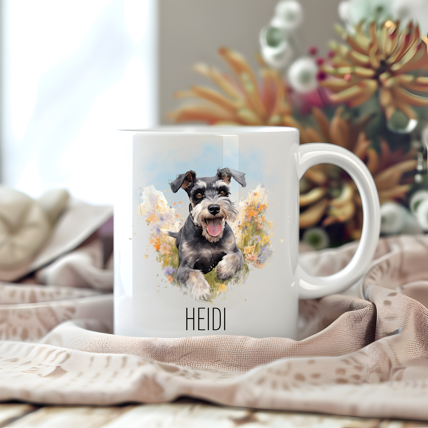 A Miniature Schnauzer is having fun in a field of flowers on a white personalised ceramic mug which has been placed on a beige cloth on a wooden surface.  Stems of large flowers decorate the background.