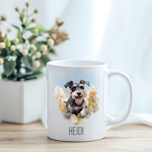 This coffee mug features a cute Miniature Schnauzer running through a field of wildflowers on a white ceramic mug which has been placed on a light wooden surface.  A green and white plant sits on the left side of the image in a square plant pot.