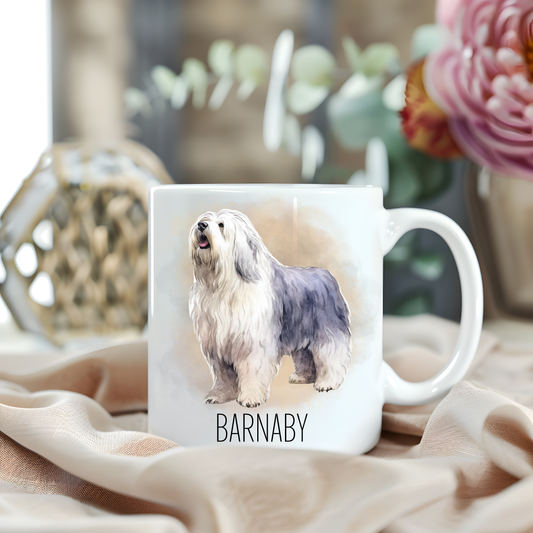 An Old English Sheepdog is stood looking to the left on a white personalised ceramic mug which has been placed on a beige cloth. A large pink flower with light green foliage accessorizes the image.