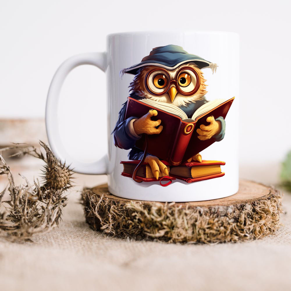 A wise Owl wearing glasses and a hat is reading a book on a white ceramic mug.  The mug is placed on a thick wooden disc and a dried thistle is set to the left hand side.