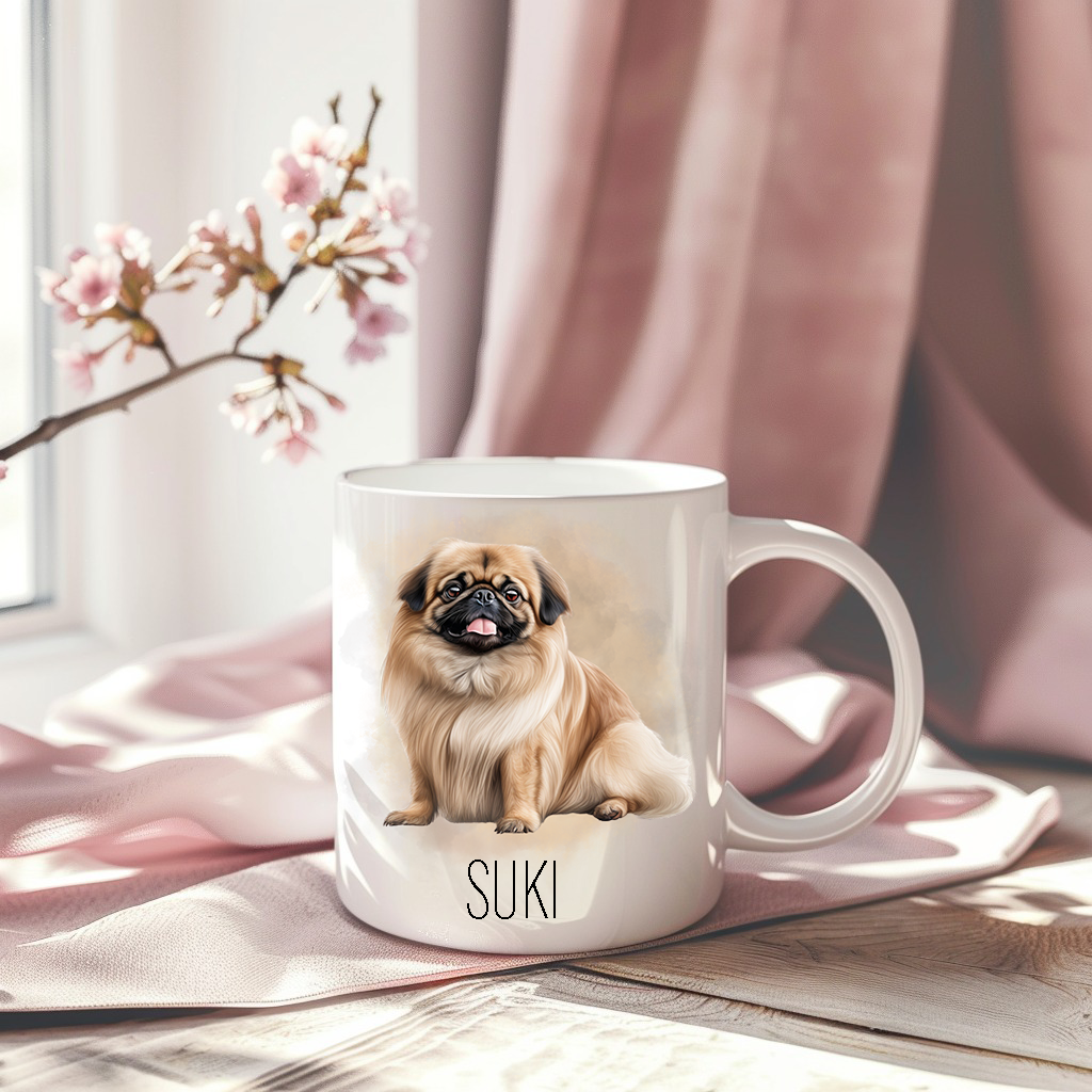 A pink drape sets the backdrop for white ceramic mug with the image of a Pekingese dog sat looking forward, mouth open and tongue out.  A stem of small pink flowers accessorizes the image