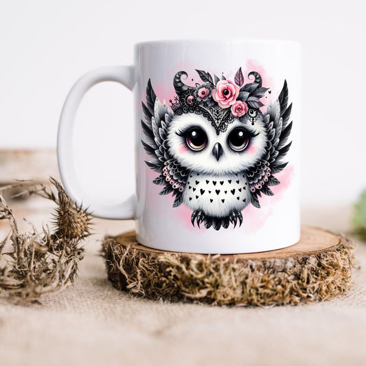 White ceramic mug showing a cute Gothic Owl with black and pink feathers, and pink roses on a pink smoky background. The mug is placed on a rustic wooden platform.