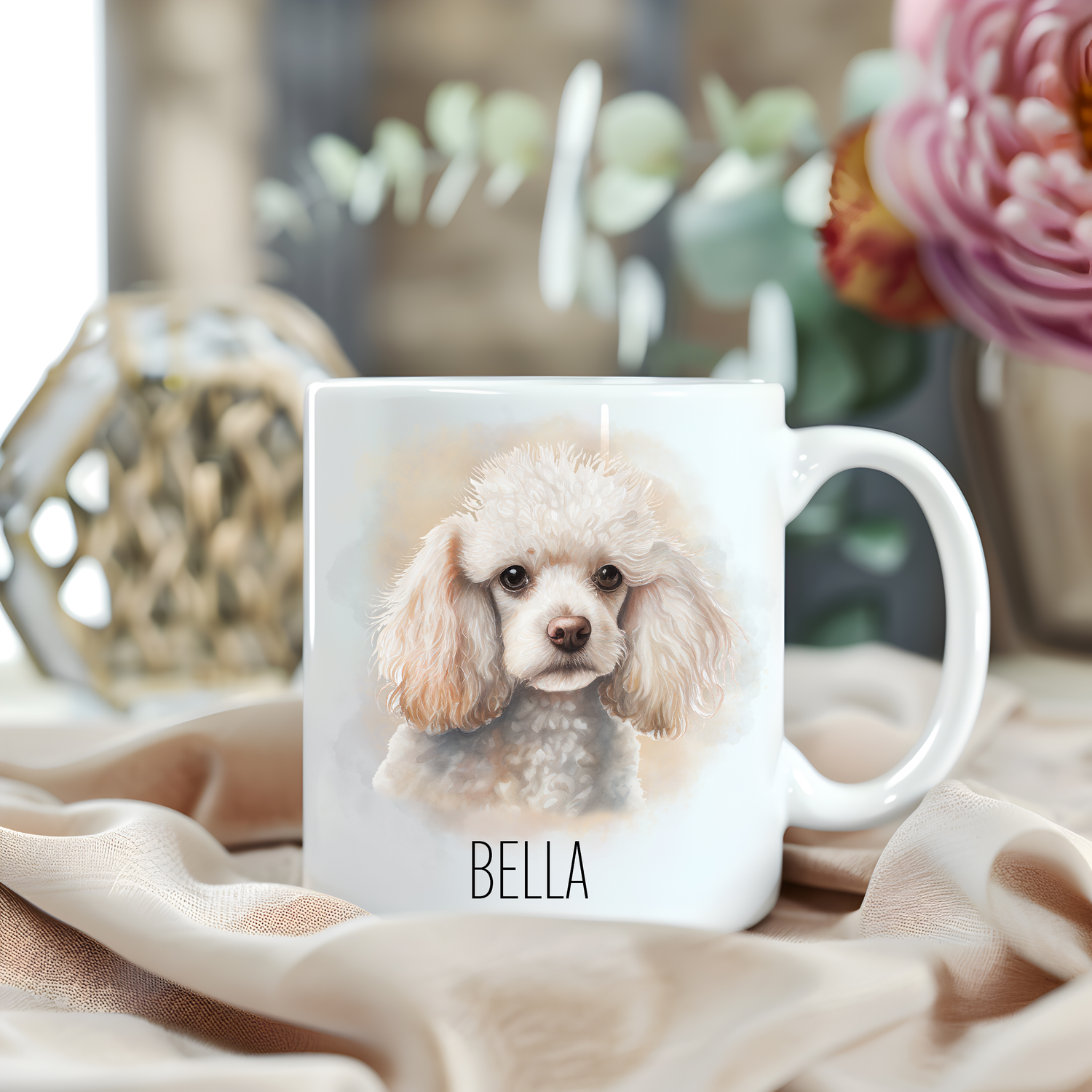 A lovely headshot of a pretty white Poodle on a white personalised ceramic mug which has been placed on a beige cloth.  A large pink flower with green foliage accessorizes the image