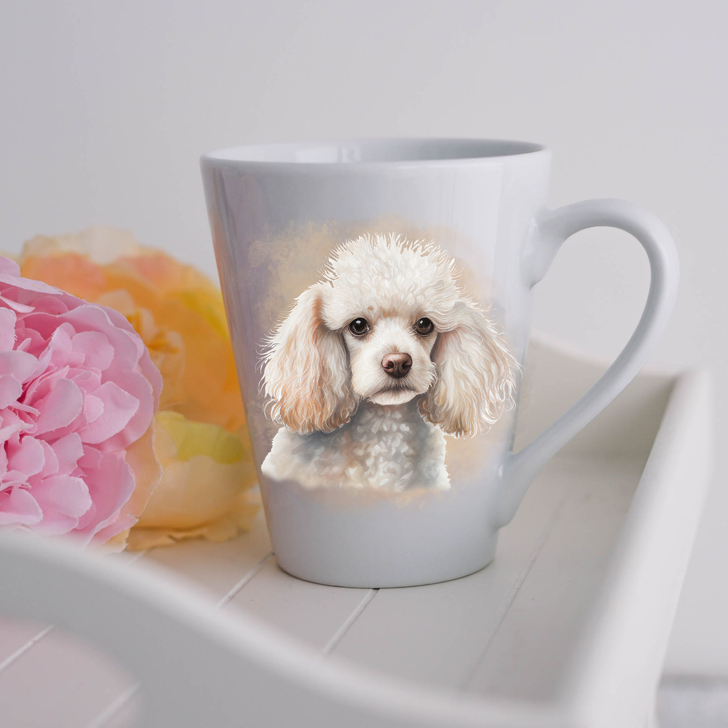 A white Miniature Poodle is showing head and shoulders is placed on a white ceramic latte mug in a smoky background and looking forward.  The mug is placed on a white tray with pink and yellow flowers. 