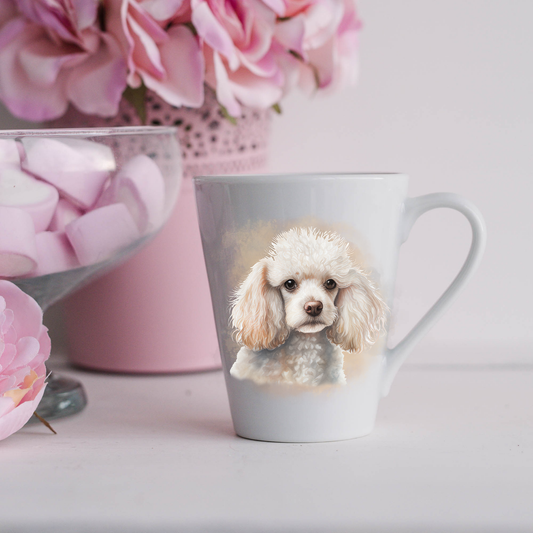 A White Miniature Poodle is shown on a white ceramic latte mug in a smoky background and looking forward.  The mug is placed on a white surface with pink flowers in a pink plant pot and a dish of pink marshmallows.