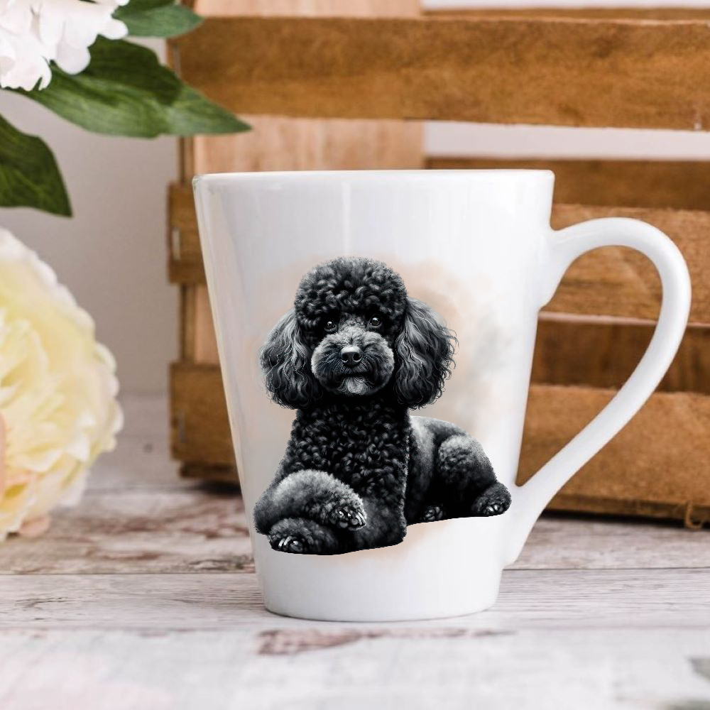 A white ceramic latte mug stands on a wooden surface with a wooden crate in the background. The mug features a Black Miniature Poodle.  A large yellow flower peeps in from the left-hand side.