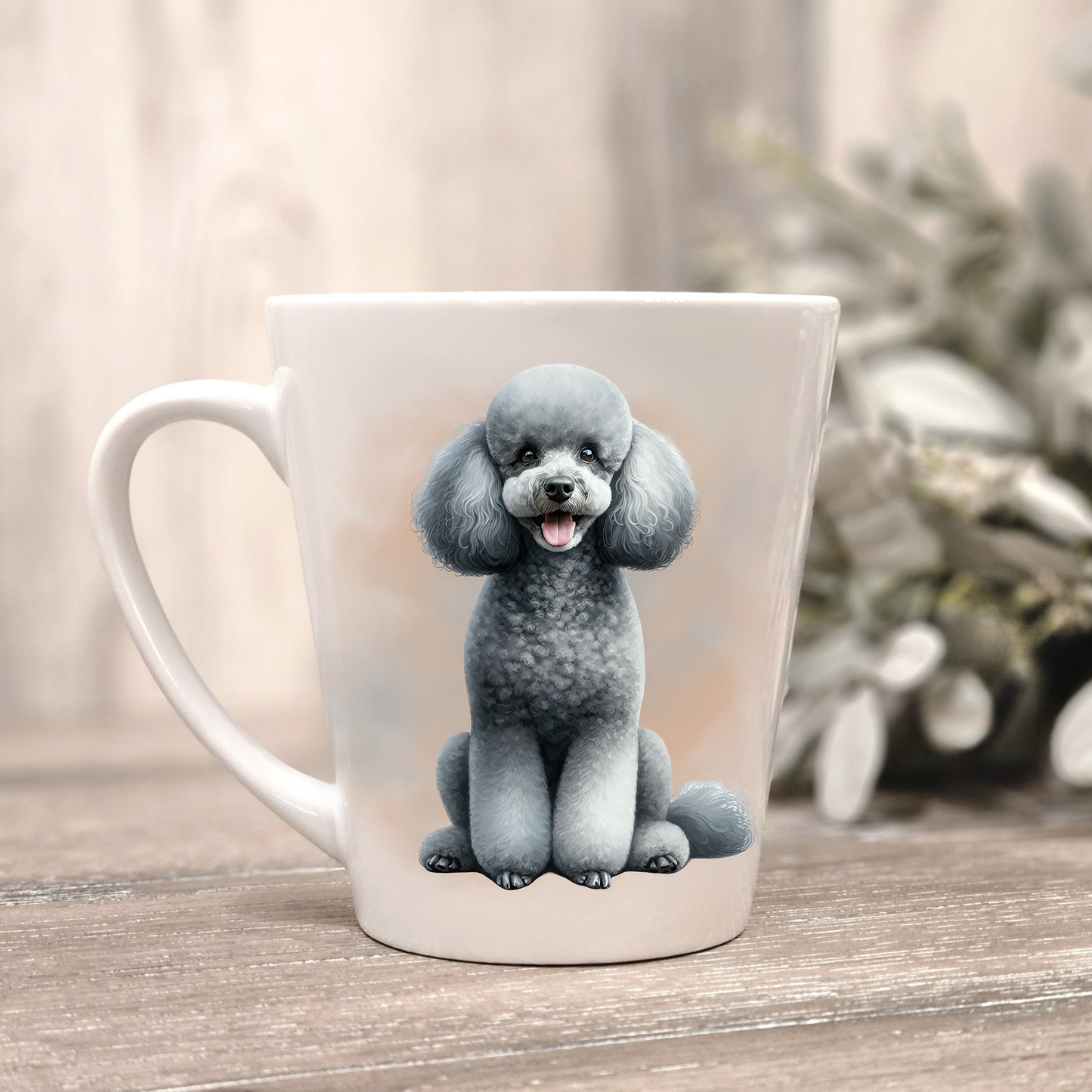 A grey Miniature Poodle is shown on a white ceramic latte mug in a smoky background and looking forward.  The mug is placed on a wooden surface with sage green foliage to the right-hand side.