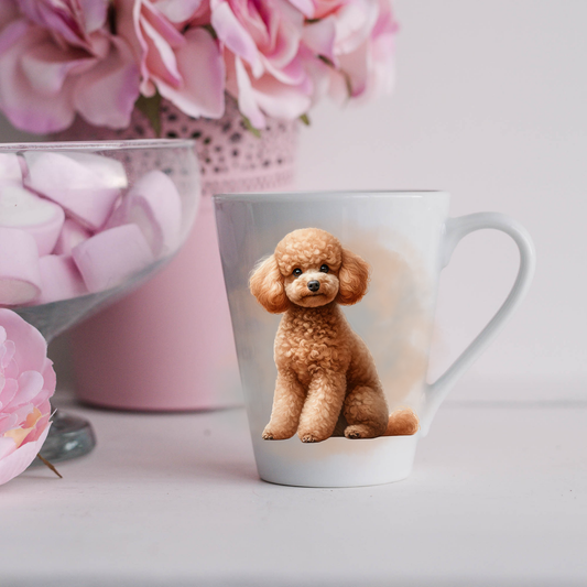 An Apricot Miniature Poodle is shown on a white ceramic latte mug in a smoky background and looking forward.  The mug is placed on a white surface with pink flowers in a pink plant pot and a dish of pink marshmallows.