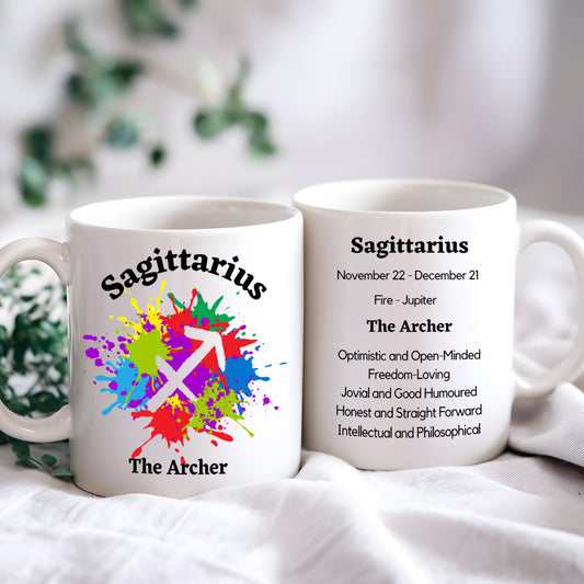 A white ceramic coffee mug with a colorful Sagittarius symbol and related text personalisation, placed on a pale surface with a floral pattern in the background.