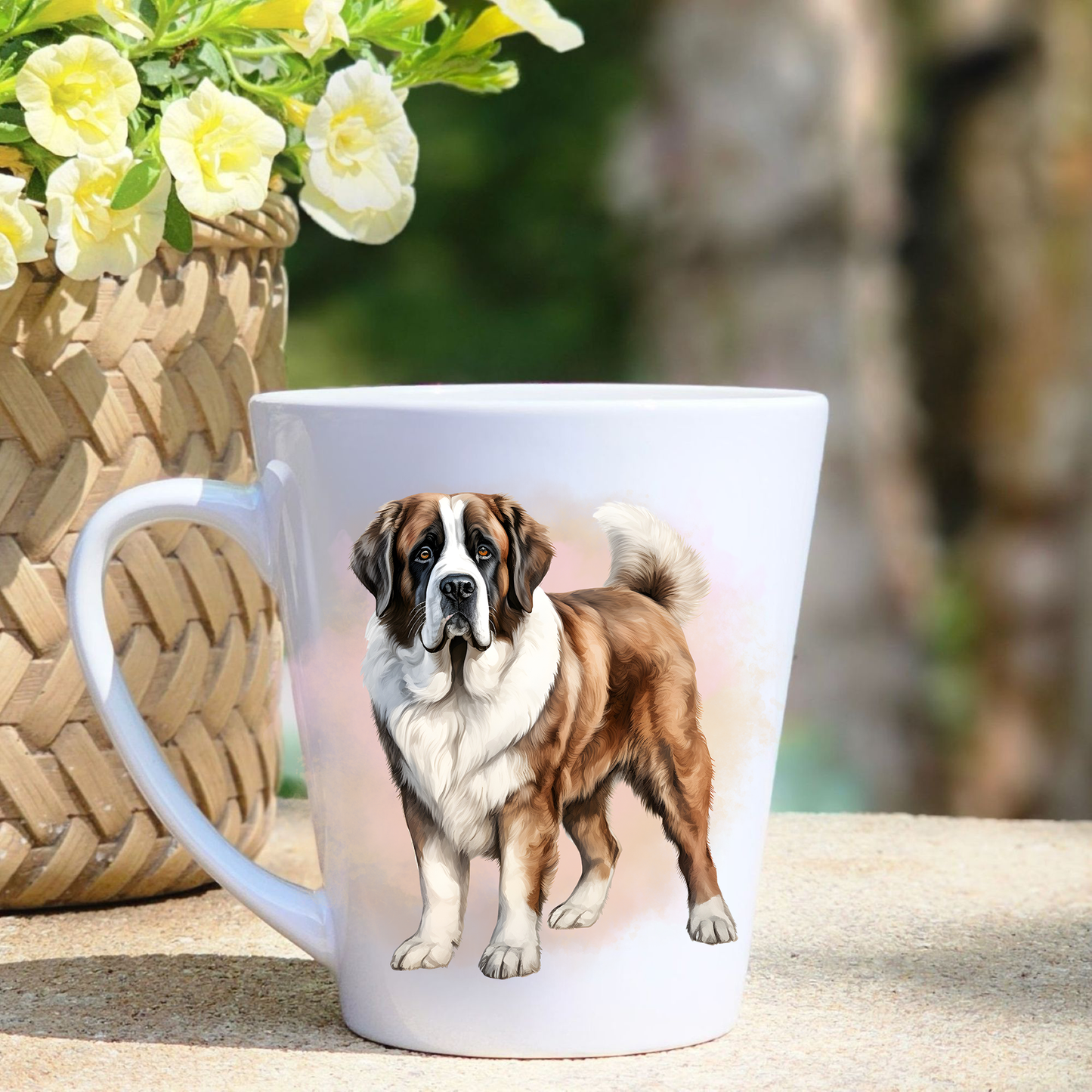 A white ceramic latte mug featuring a Saint Bernard in a beige mist background.  A basket containing yellow flowers sits to the left-hand side. 