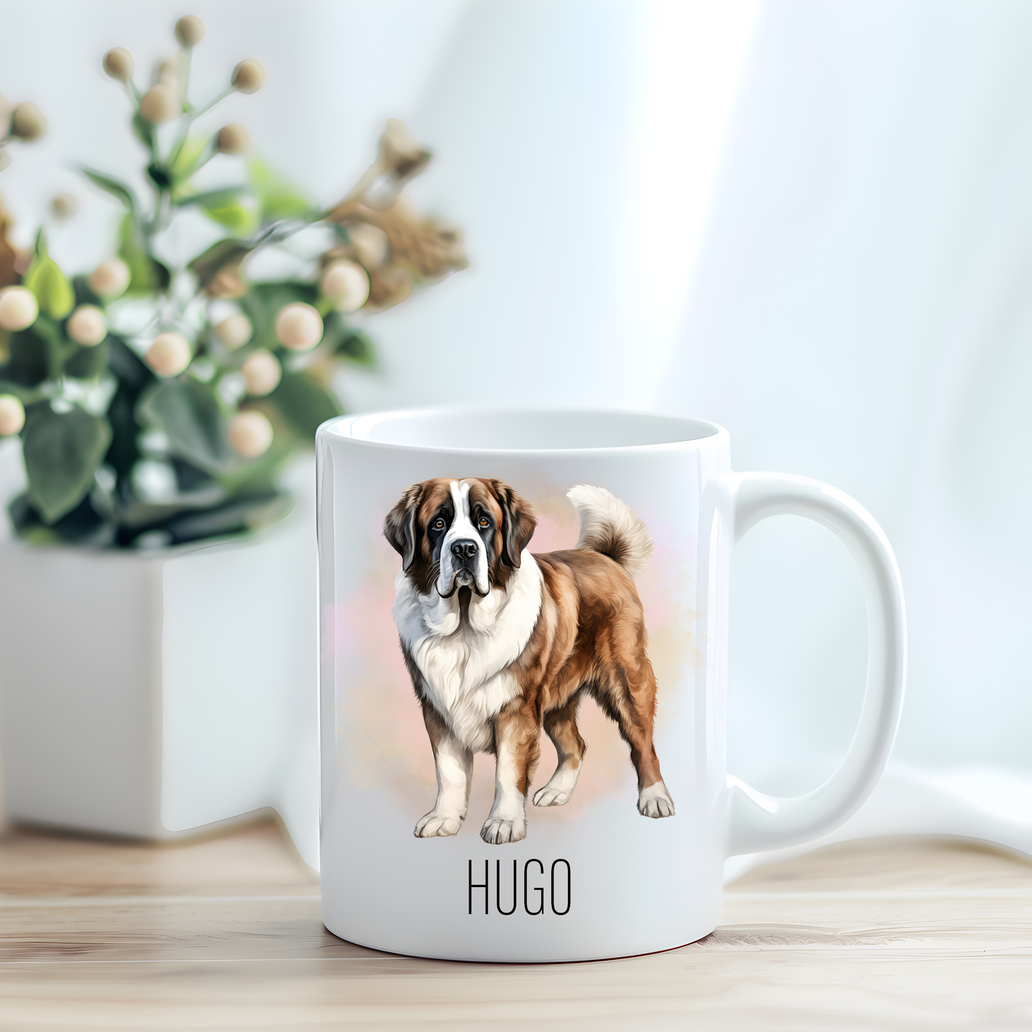 This coffee mug features a Saint Bernard on a white ceramic mug which has been placed on a light wooden surface.  The background is accessorized by a green and white plant sat in a square plant pot.