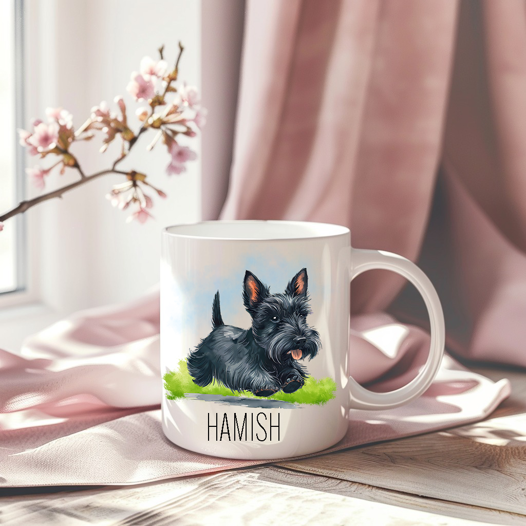 A pink drape sets the background for white ceramic mug with the image of a happy black Scottish Terrier running across grass, mouth open and tongue out.  A stem of small pink flowers accessorizes the image.