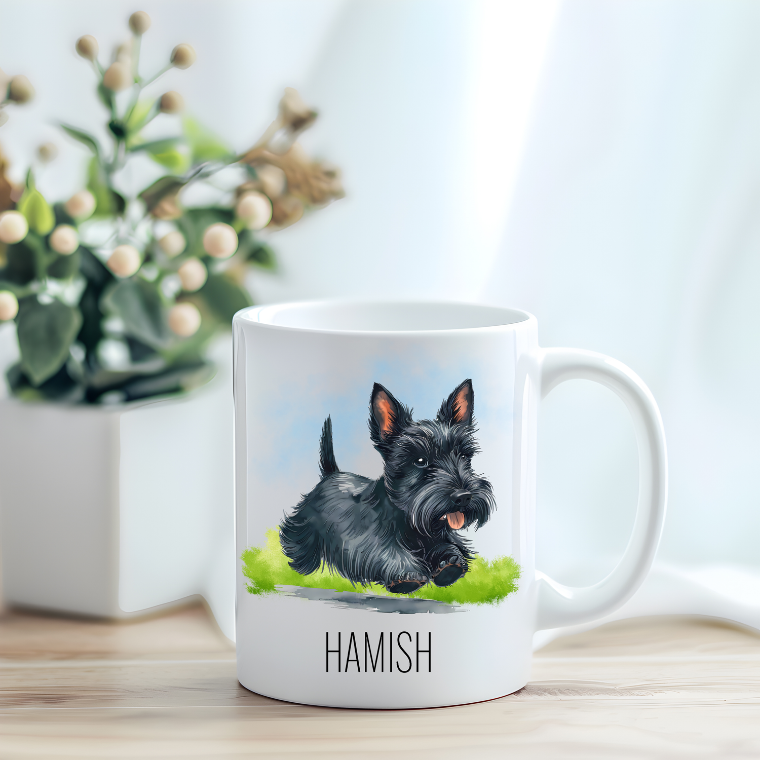 This coffee mug features a black Scottish Terrier on a white ceramic mug which has been placed on a light wooden surface.  A green and white plant sits on the left side of the image in a square plant pot.
