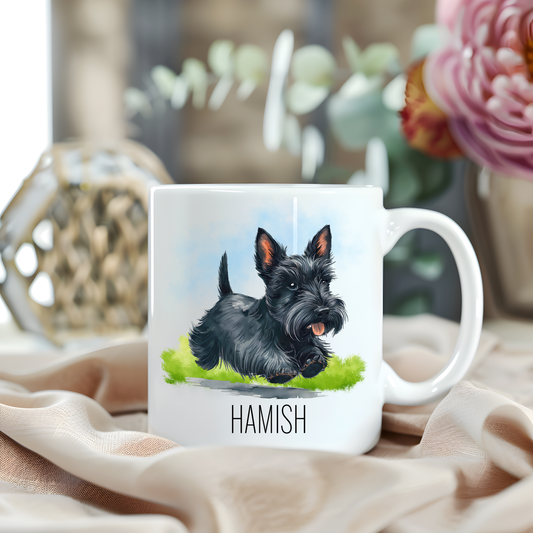 A black Scottish Terrier is running to its left over grass and is placed on a white personalised ceramic mug. The mug sits on a beige cloth with a large pink flower and green foliage accessorizing the background.