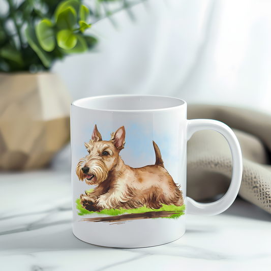 This coffee mug features a wheaten Scottish Terrier on a white ceramic mug which has been placed on a grey marble surface.  A green plant sits in the left corner.