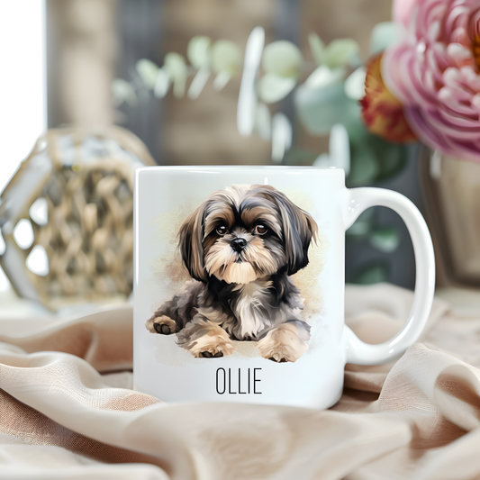 A Shih Tzu laid looking forward is placed on a white personalised ceramic mug.  The mug sits on a beige cloth with a large pink flower and green foliage accessorizing the background.