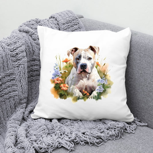 White sofa cushion with an image of a parti-colour Staffordshire Bull Terrier laid in among flowers and facing forward. The cushion is placed on a grey sofa with a grey blanket draped across the corner