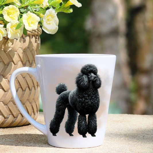 A white ceramic latte mug featuring a black Standard Poodle in a beige mist background.  A basket containing yellow flowers sits to the left-hand side.