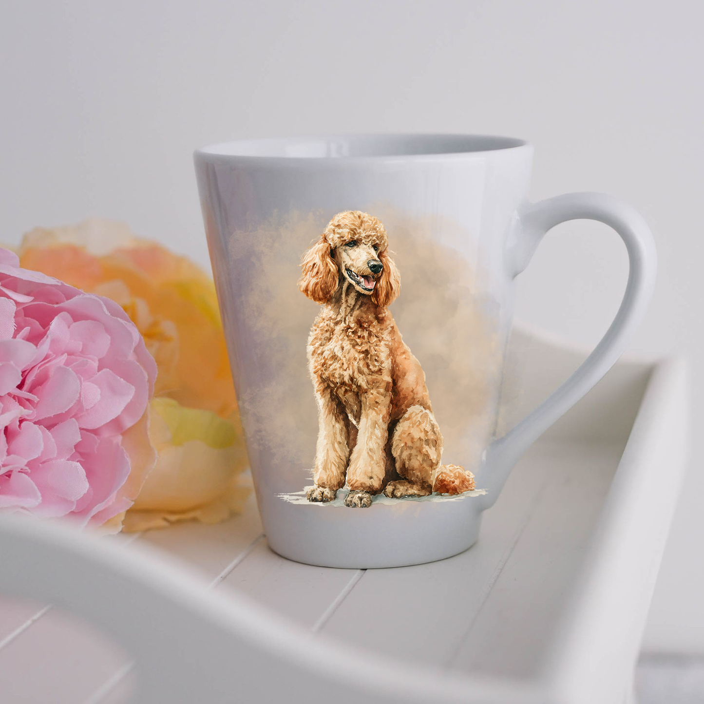 An Apricot Standard Poodle is in a seated position and is placed on a white ceramic latte mug in a smoky background and looking to its left.  The mug is placed on a white tray with pink and yellow flowers.