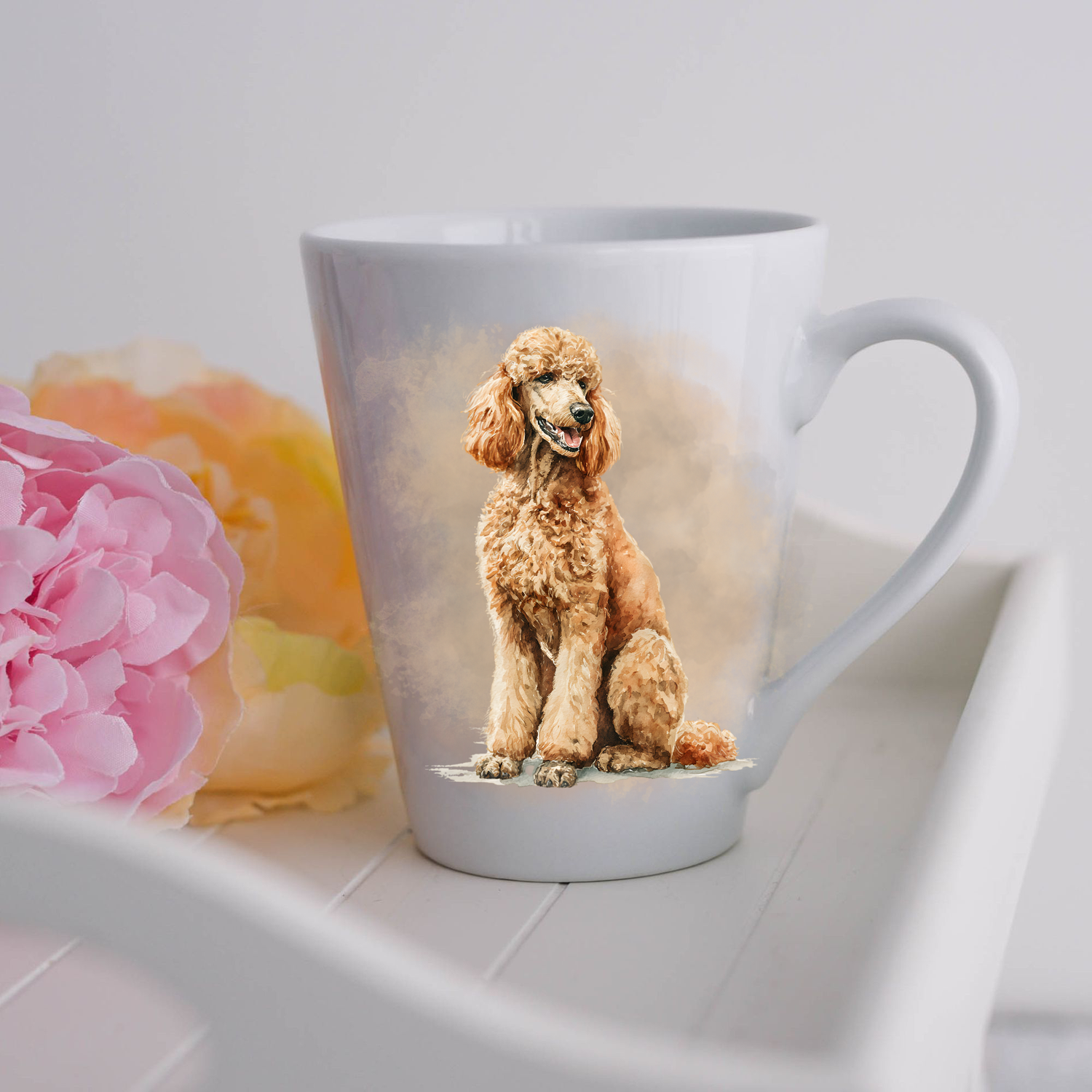 An Apricot Standard Poodle is in a seated position and is placed on a white ceramic latte mug in a smoky background and looking to its left.  The mug is placed on a white tray with pink and yellow flowers.