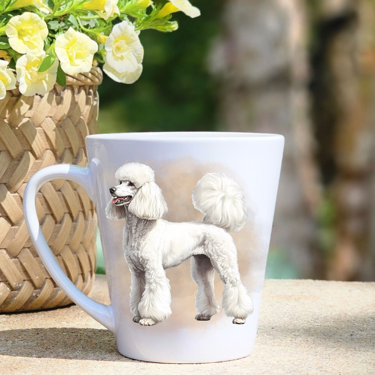 A white ceramic latte mug featuring a white Standard Poodle in a beige mist background.  A basket containing yellow flowers sits to the left-hand side.