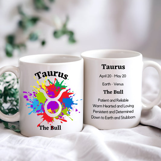 Two mugs with Taurus zodiac design and information on a white surface.