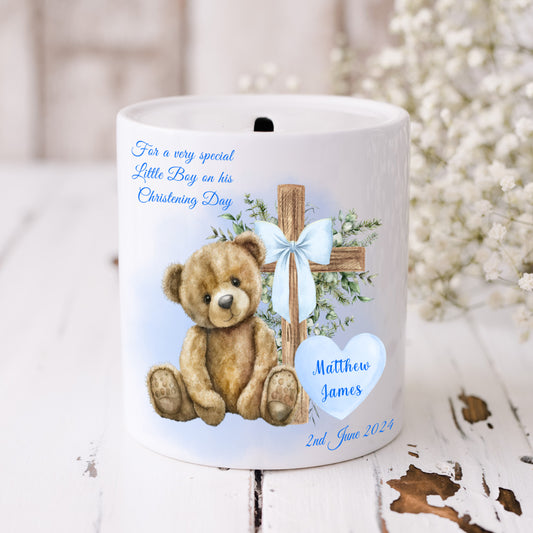 Personalised Christening money box for a boy. Teddy bear and cross with a blue ribbon bow.  Floral background.