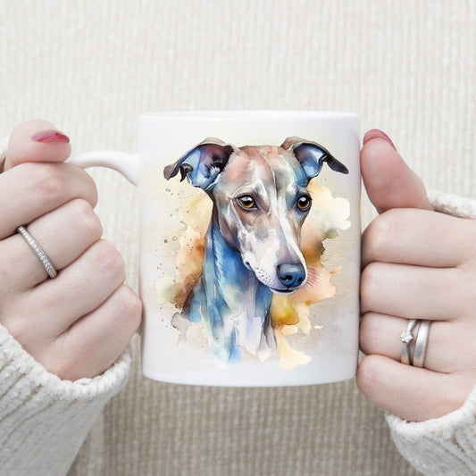 A watercolour image of a Whippet head with an alert expression adorns this white ceramic mug. A cloudy background decorates the mug which is being held by a woman with both hands.