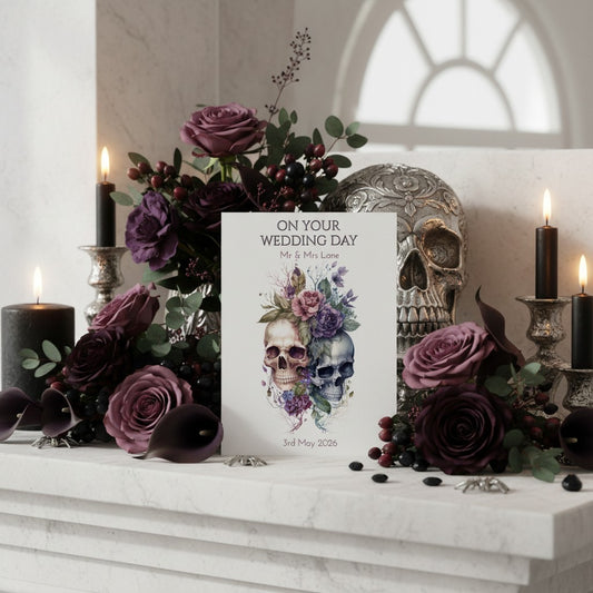 Decorative setup with skull and floral design on a wedding card, surrounded by purple roses and candles.