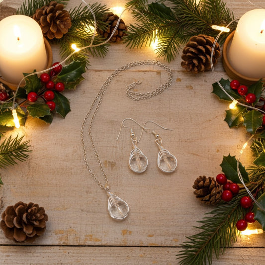 Silver April birthstone jewellery set with necklace and earrings on a wooden surface with Christmas decorations.