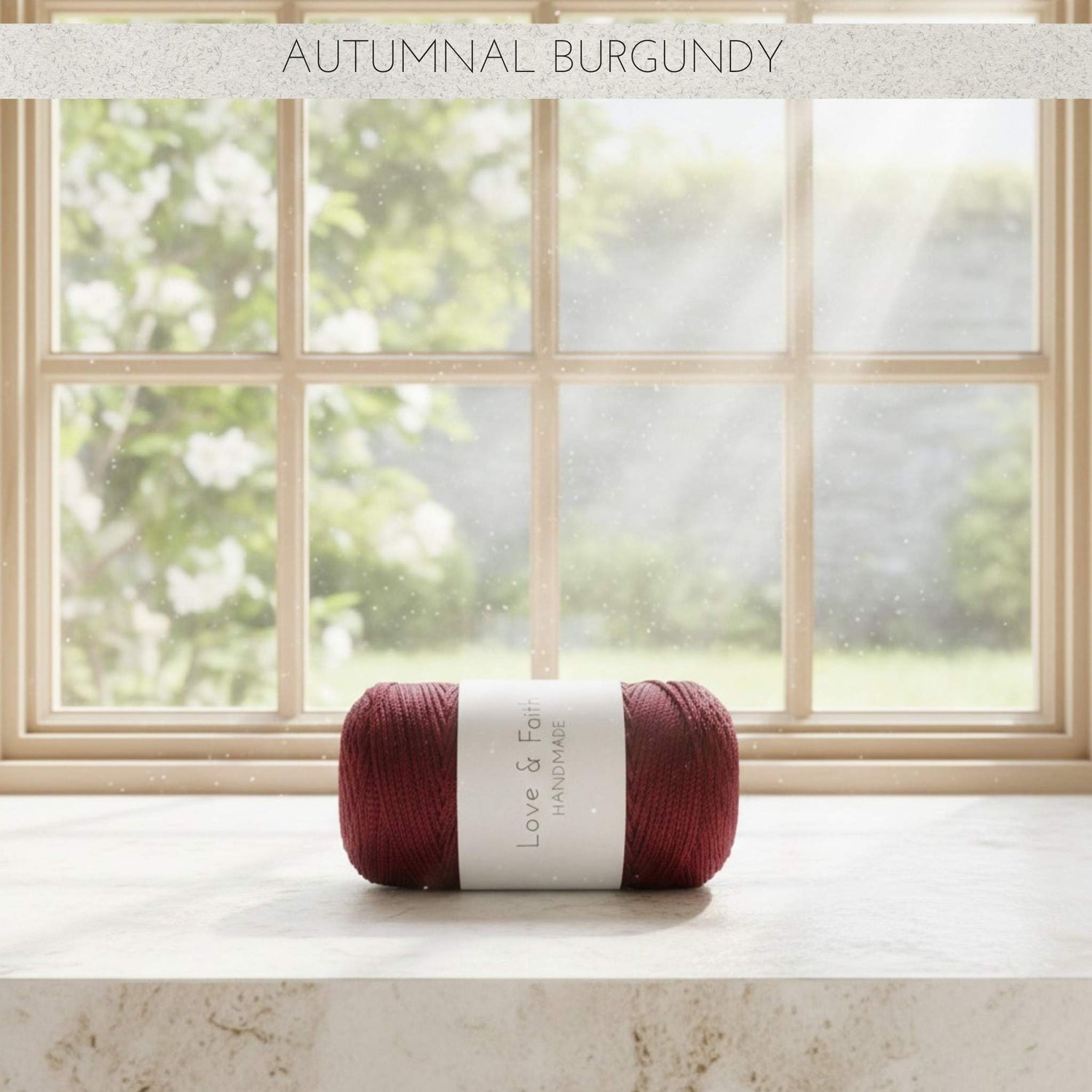 Ball of yarn labelled 'Autumnal Burgundy' on a surface with a window in the background