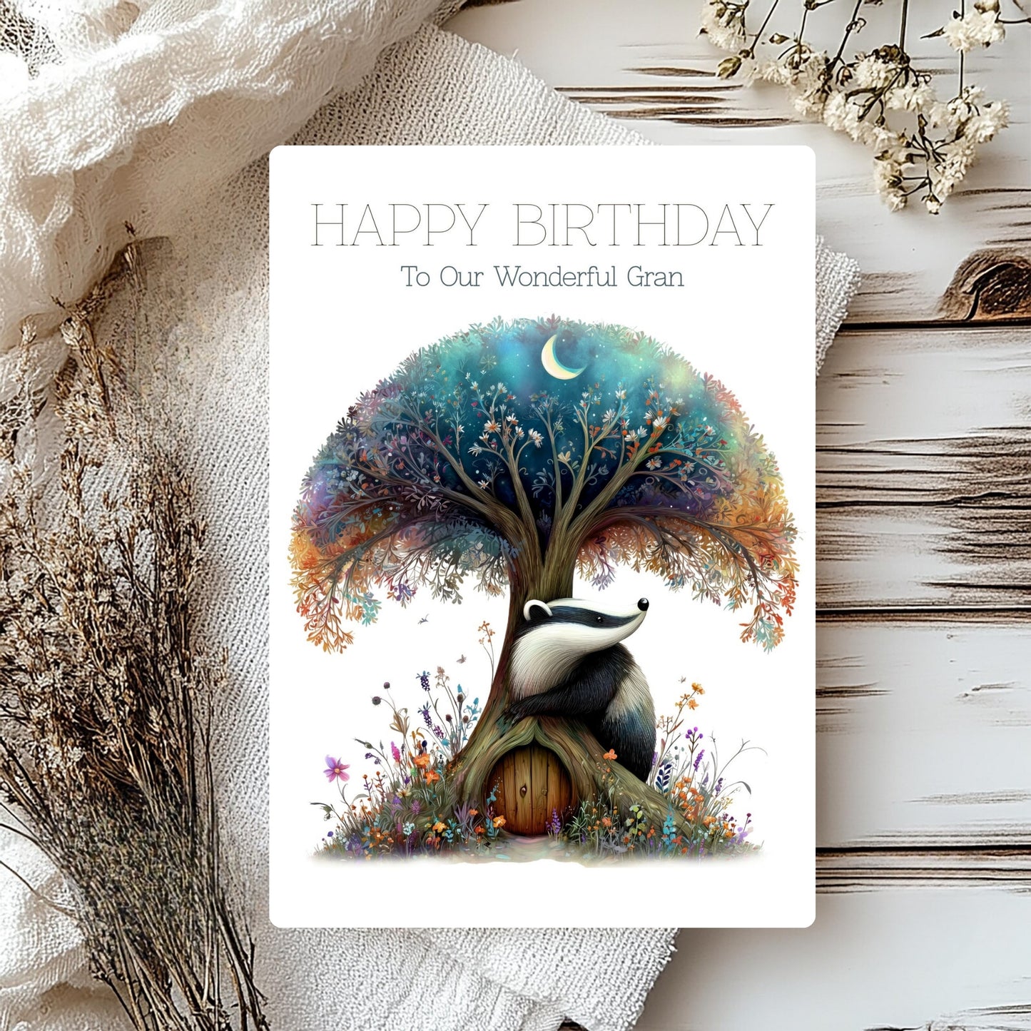 Birthday card with a badger under a tree, surrounded by flowers and text on a rustic background.