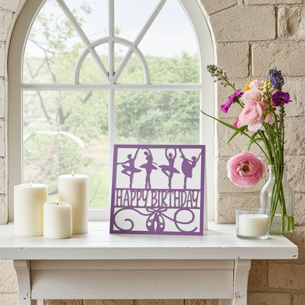 A purple 'Happy Birthday' sign featuring ballerina silhouettes, displayed on a white mantelpiece next to candles, flowers, and a brick wall window.