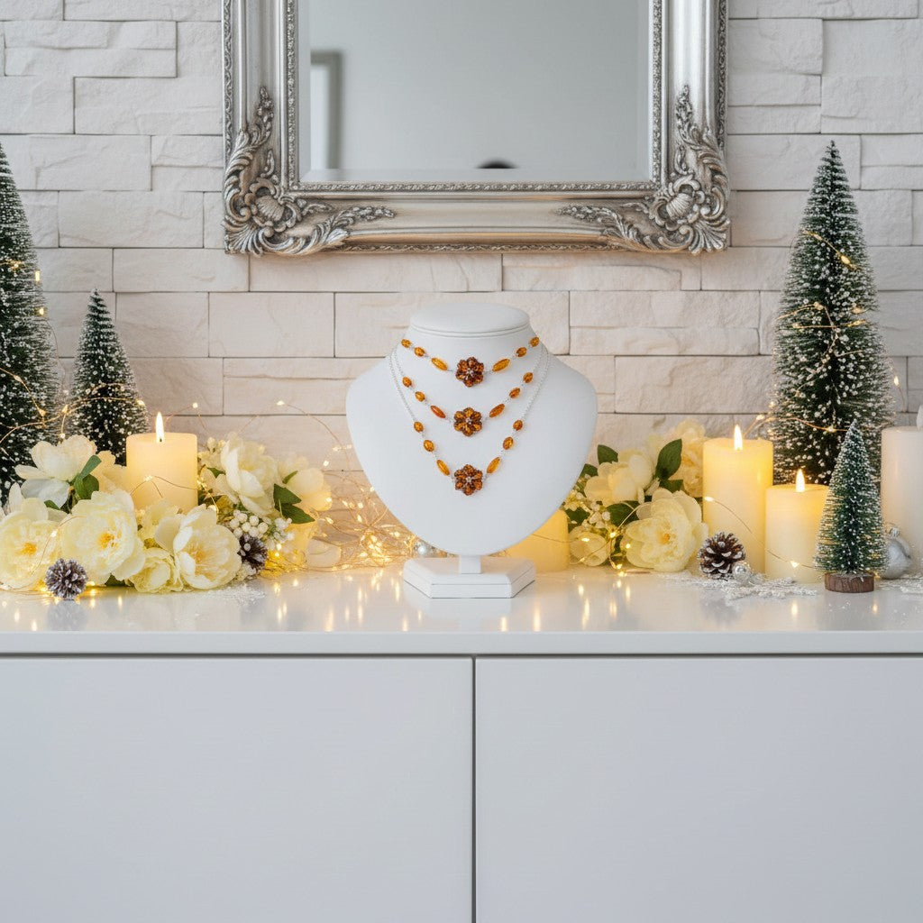Jewellery display with necklaces on a white stand, surrounded by candles and decorative trees in a festive setting.