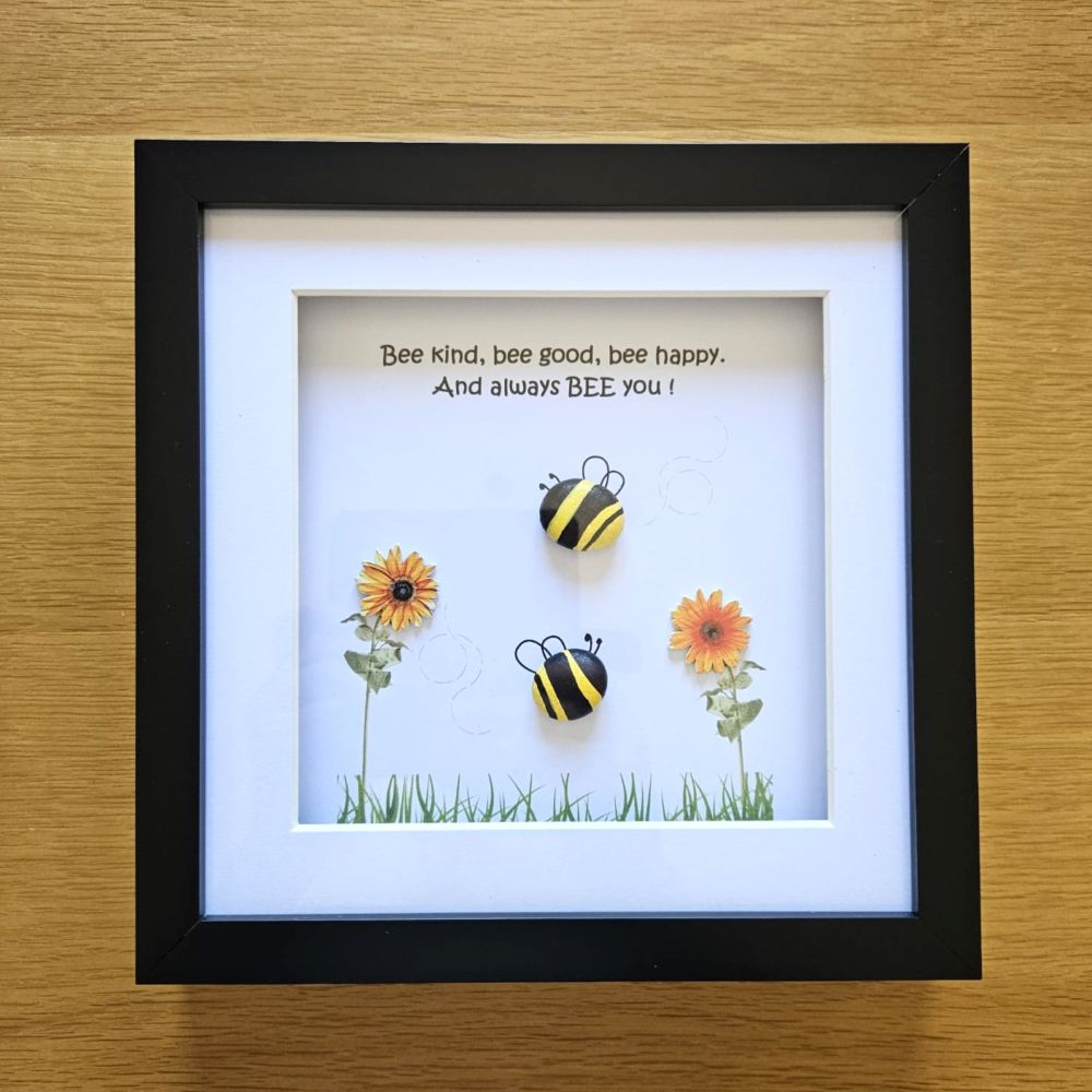 Framed artwork with two bees and flowers on a wooden surface