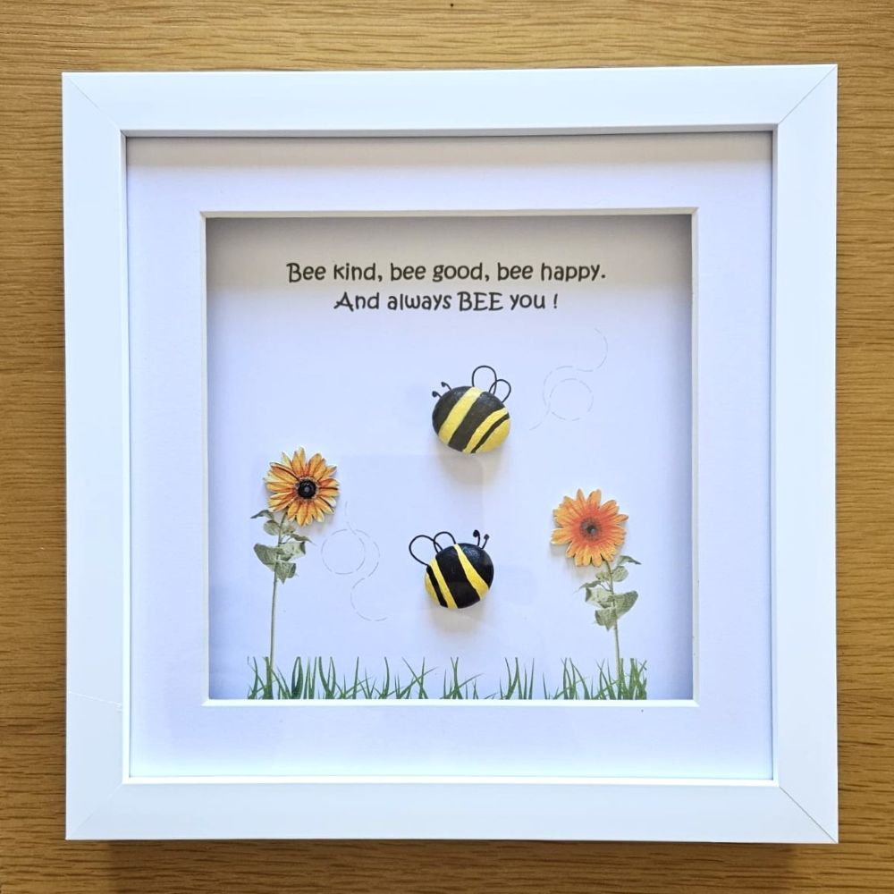 Framed artwork with bees and flowers on a wooden surface